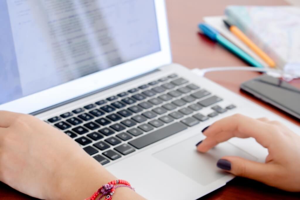 mesa de trabalho com notebook, mãos digitando representando pesquisa de temas